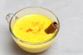 Closeup image of indian spiced drink turmeric golden milk with cinnamon stick on grey concrete background