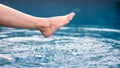 Legs and barefoot kicking and splashing water in the pool