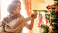 Closeup image of little boy adorning Christmas tree with mother