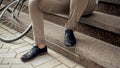 Closeup photo of male feet sitting on stone stairs next to bicycle Royalty Free Stock Photo