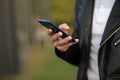 Closeup image of male hands with smartphone, searching internet or social networks, blurred background