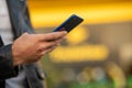 Closeup image of male hands with smartphone, searching internet or social networks, blurred background