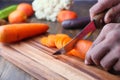 Closeup image of a man cutting and chopping carrot by knife on wooden board Royalty Free Stock Photo