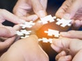 Closeup image of many people hands holding a jigsaw puzzle piece in circle together with sunlight effect Royalty Free Stock Photo