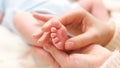 Closeup image of mother massaging little feet of her newborn baby boy lying on bed Royalty Free Stock Photo