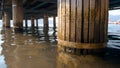 Closeup image of old collapsing wooden columns holding pier on the beach Royalty Free Stock Photo