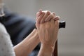 Closeup image old female hands holding walking stick seated indoors