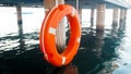 Closeup image of orange lifesaving buoy hanging on long wooden pier at sea beach Royalty Free Stock Photo