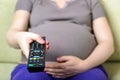 Closeup image of a pregnant woman hand holding remote control Royalty Free Stock Photo