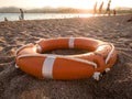 Closeup photo of red plastic life saving ring on sand of the sea beach against beautiful sunset over the ocean Royalty Free Stock Photo