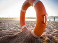 Closeup photo of red plastic life saving ring on sand of the sea beach against beautiful sunset over the ocean Royalty Free Stock Photo