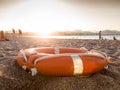 Closeup image of red plastic life saving ring on sandy sea beach at sunset light Royalty Free Stock Photo