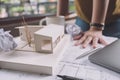 Closeup image of a stressed architects thinking and drawing shop drawing paper with architecture model and laptop on table Royalty Free Stock Photo