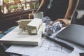 Closeup image of a stressed architects thinking and drawing shop drawing paper with architecture model and laptop on table Royalty Free Stock Photo