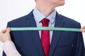Closeup image of tailor taking measurements for business jacket suit. Businessman in red tie and blue suit at studio isolated