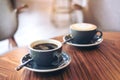 Closeup image of two blue cups of hot latte coffee and Americano coffee on vintage wooden table Royalty Free Stock Photo