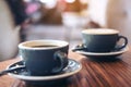 Closeup image of two blue cups of hot latte coffee and Americano coffee on vintage wooden table