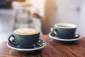 Closeup image of two blue cups of hot latte coffee and Americano coffee on vintage wooden table Royalty Free Stock Photo