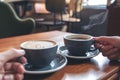 Two people`s hands holding coffee and hot chocolate cups on wooden table in cafe Royalty Free Stock Photo