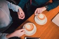 Closeup image of two people& x27;s hands holding coffee cups on wooden table in cafe. Royalty Free Stock Photo