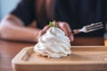 Closeup image of whipped cream on wooden plate with a woman holding fork