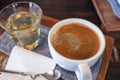 A white cup of hot coffee and a glass of tea on vintage wooden table in cafe Royalty Free Stock Photo