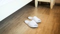 Closeup image of white slippers near bed at hotel room Royalty Free Stock Photo