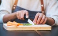 a woman cutting and chopping asparagus and carrot by knife on wooden board Royalty Free Stock Photo