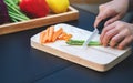 A woman cutting and chopping asparagus and carrot by knife on wooden board Royalty Free Stock Photo