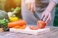 A woman cutting and chopping tomato by knife on wooden board Royalty Free Stock Photo