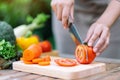 A woman cutting and chopping tomato by knife on wooden board Royalty Free Stock Photo