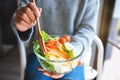 A woman eating and holding a bowl of fresh mixed vegetables salad by fork Royalty Free Stock Photo