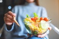 A woman eating and holding a bowl of fresh mixed vegetables salad by fork Royalty Free Stock Photo