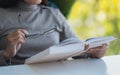 A woman holding eye glasses while reading book Royalty Free Stock Photo