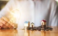 A woman holding a light bulb with house models on pile of coins for saving money concept Royalty Free Stock Photo