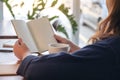 A woman holding and opening a blank notebook with coffee cup and papers on the table Royalty Free Stock Photo