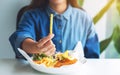 A woman holding a piece of french fries and fish and chips on table in the restaurant