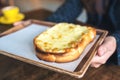 Closeup image of a woman holding a piece of sliced bread toast with cheese