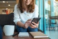 A woman holding , using and texting message from smart phone in cafe Royalty Free Stock Photo