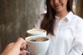 A woman and a man clink white coffee mugs in cafe Royalty Free Stock Photo