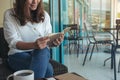 A woman opening a book to read with notebooks and coffee cup on wooden table in cafe Royalty Free Stock Photo