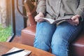 A woman opening a book to read with notebooks and coffee cup on wooden table in cafe Royalty Free Stock Photo