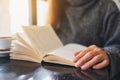 A woman opening and reading a vintage novel book on the table