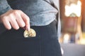 A woman picking up and dropping bitcoin into a black jean pocket