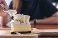 Closeup image of a woman`s hand cutting white chocolate cheese cake with fork on wooden plate Royalty Free Stock Photo