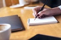 Woman`s hand writing on a blank notebook with laptop , tablet and coffee cup on wooden table background Royalty Free Stock Photo