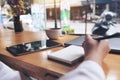 Closeup image of woman`s hand writing on a blank notebook with laptop , tablet and coffee cup on wooden table Royalty Free Stock Photo