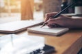 Closeup image of woman`s hand writing on a blank notebook with laptop , tablet and coffee cup on wooden table Royalty Free Stock Photo