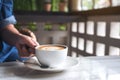 Woman`s hands holding a cup of hot coffee with heart latte art on table in cafe Royalty Free Stock Photo