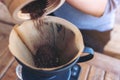 Woman`s hands pouring coffee grounds from wooden grinder into a drip coffee filter Royalty Free Stock Photo